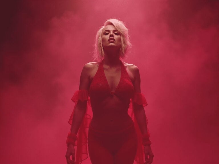 Seductive woman in red lingerie with pink smoky background, empowering confidence and self-love.