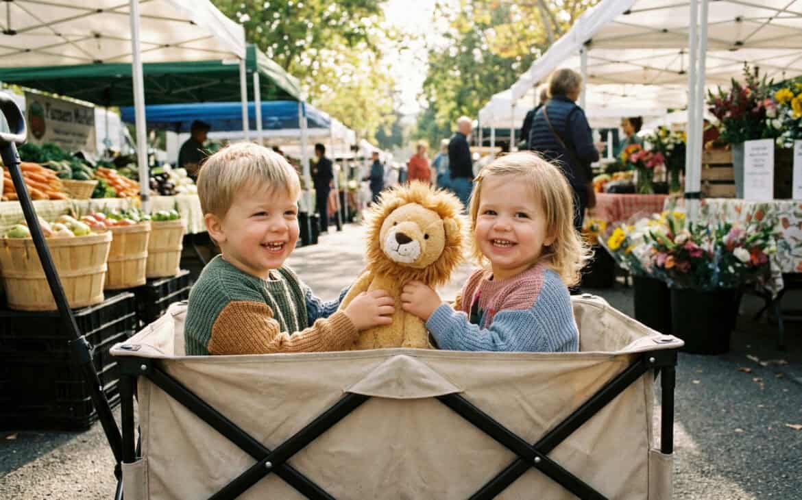 Two toddlers riding in a stroller wagon at an outdoor market