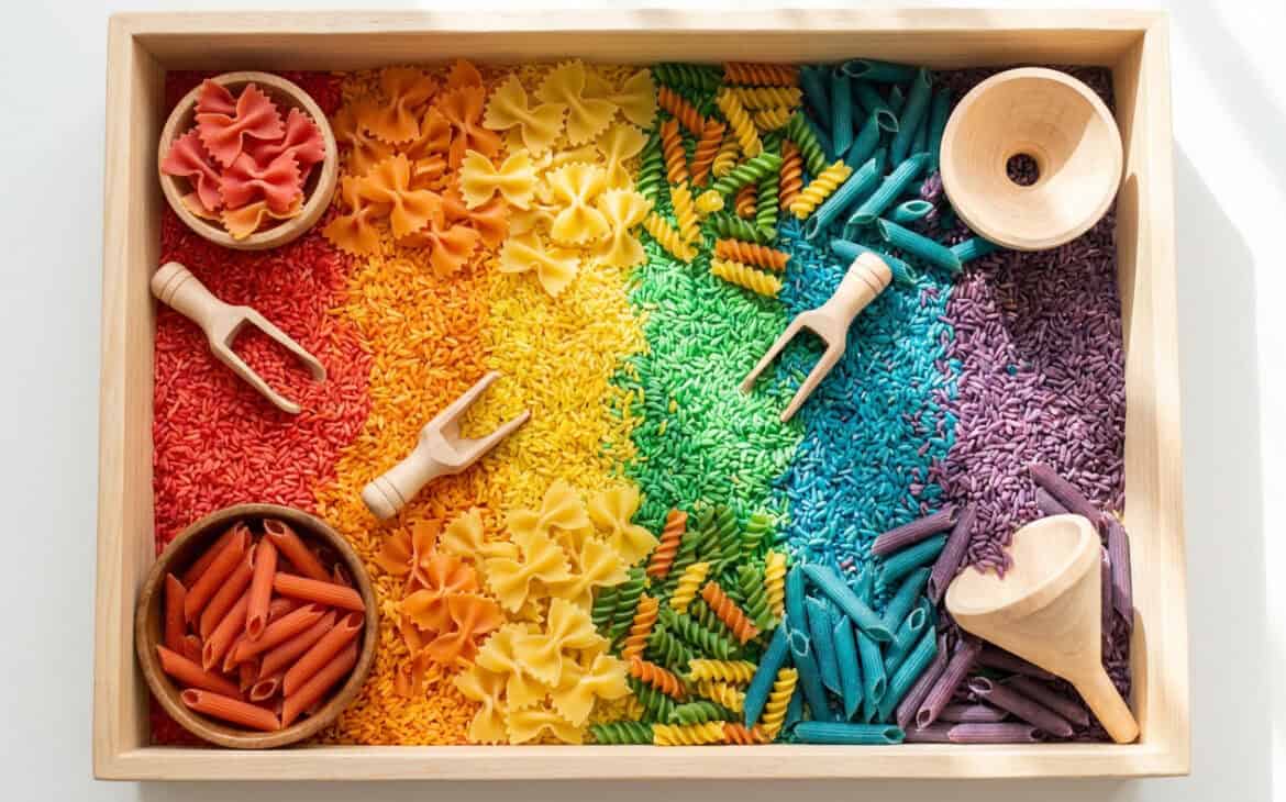 Close-up of rainbow-dyed rice and pasta with scoops and funnels